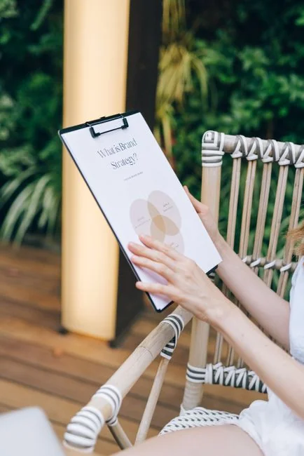 Person analyzes stock data with a smartphone and laptop, indoors.